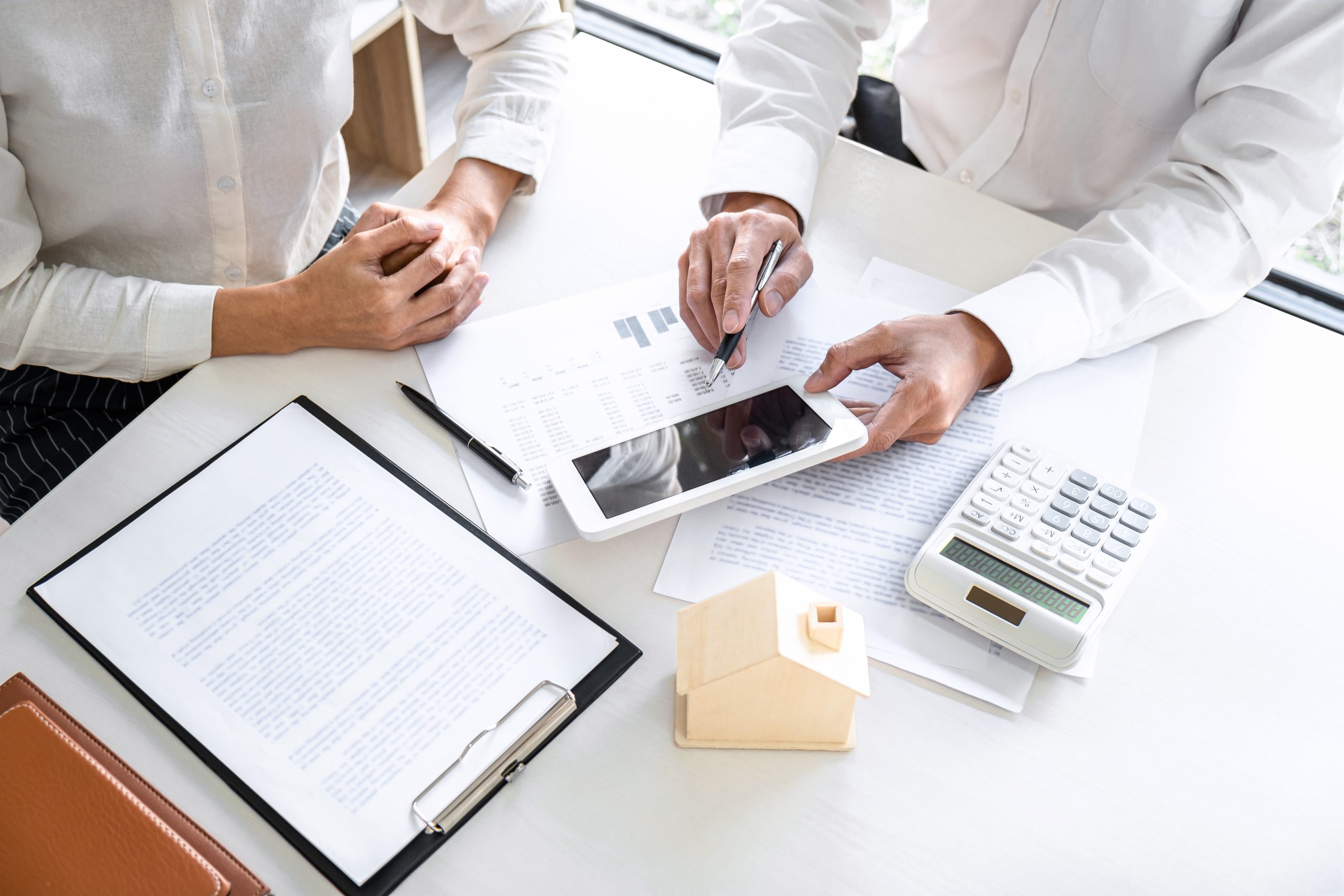 Real estate broker agent presenting and consult to customer to decision making sign insurance form agreement, home model, concerning mortgage loan offer for and house insurance.
