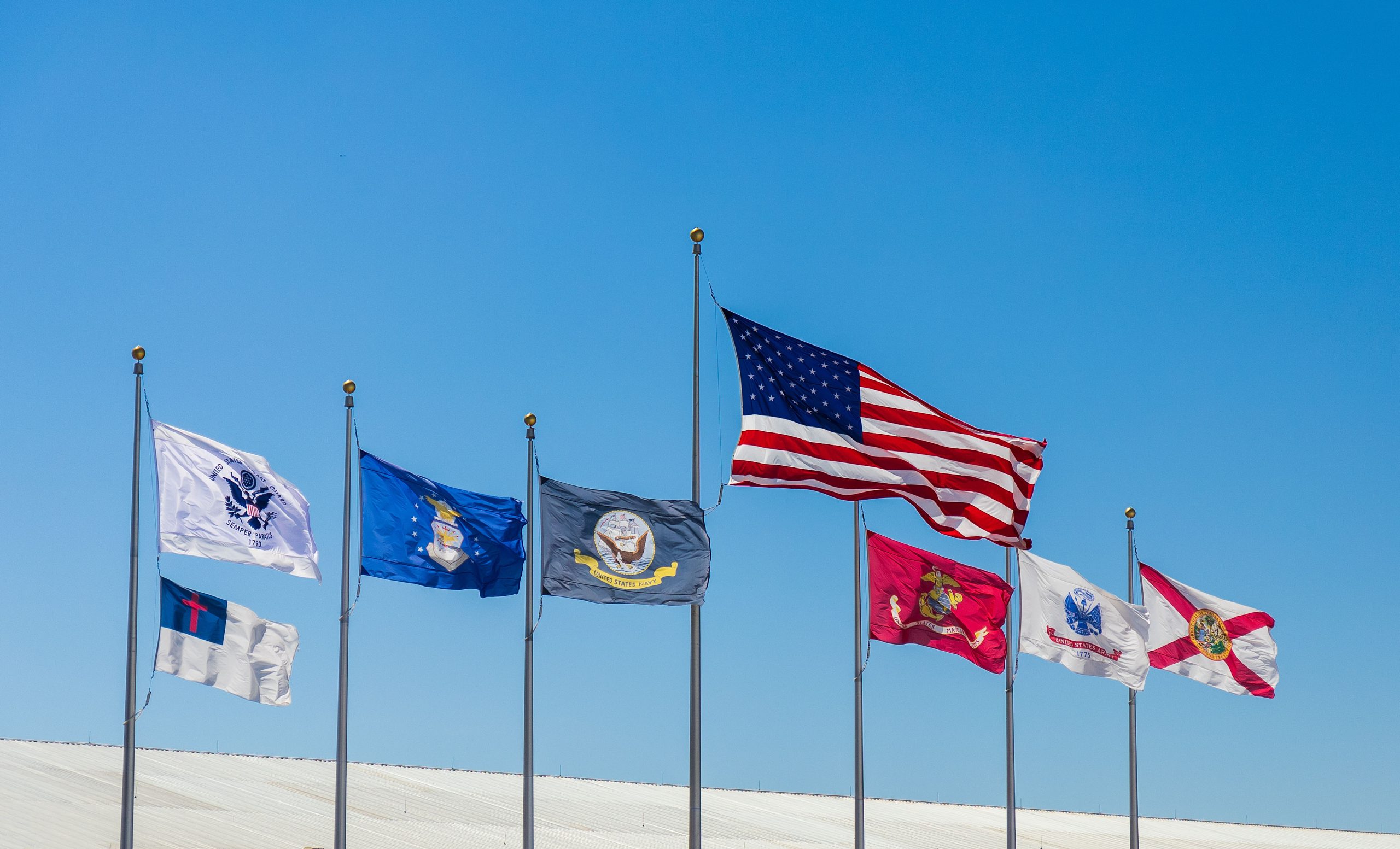 United States Flag, Florida State Flag, Christian Flag and Armed Forces Flags flies on sunny day with blue skies..