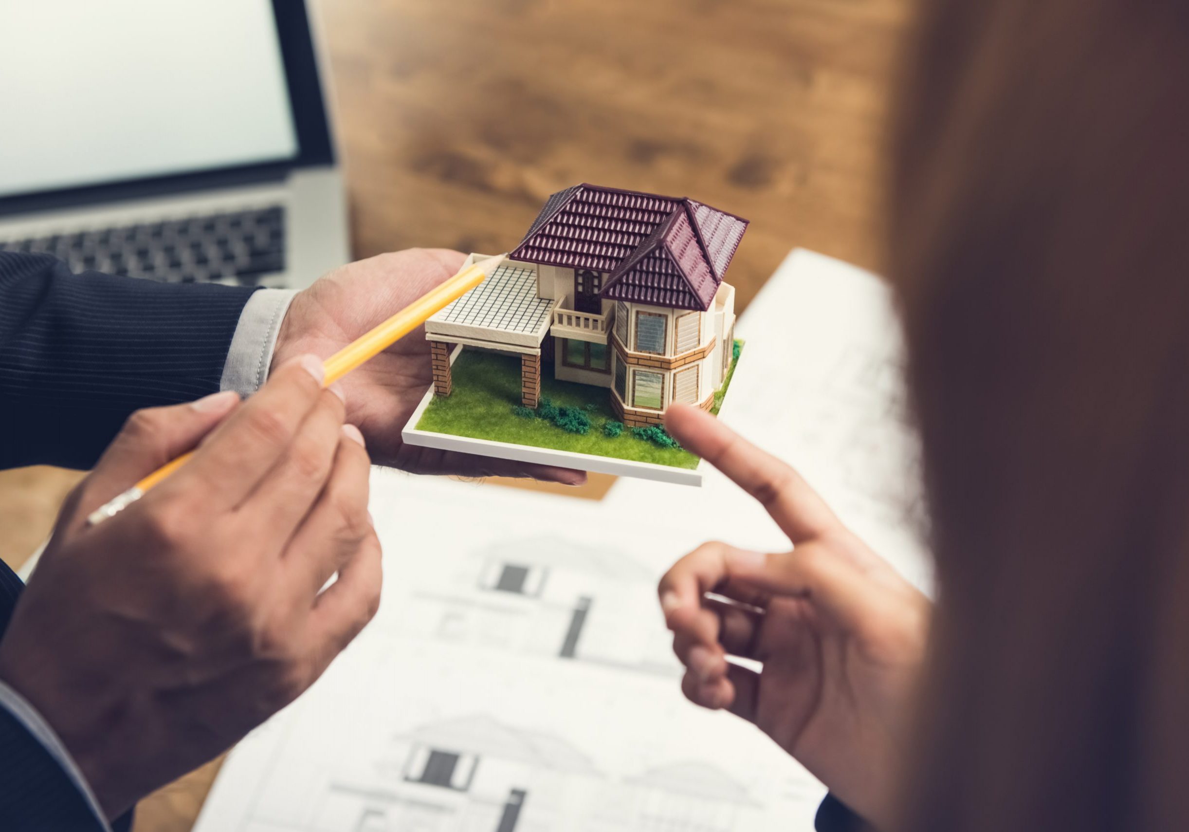 Housing developer agent holding an architectural model and explaining concept to client or architect for real estate development.